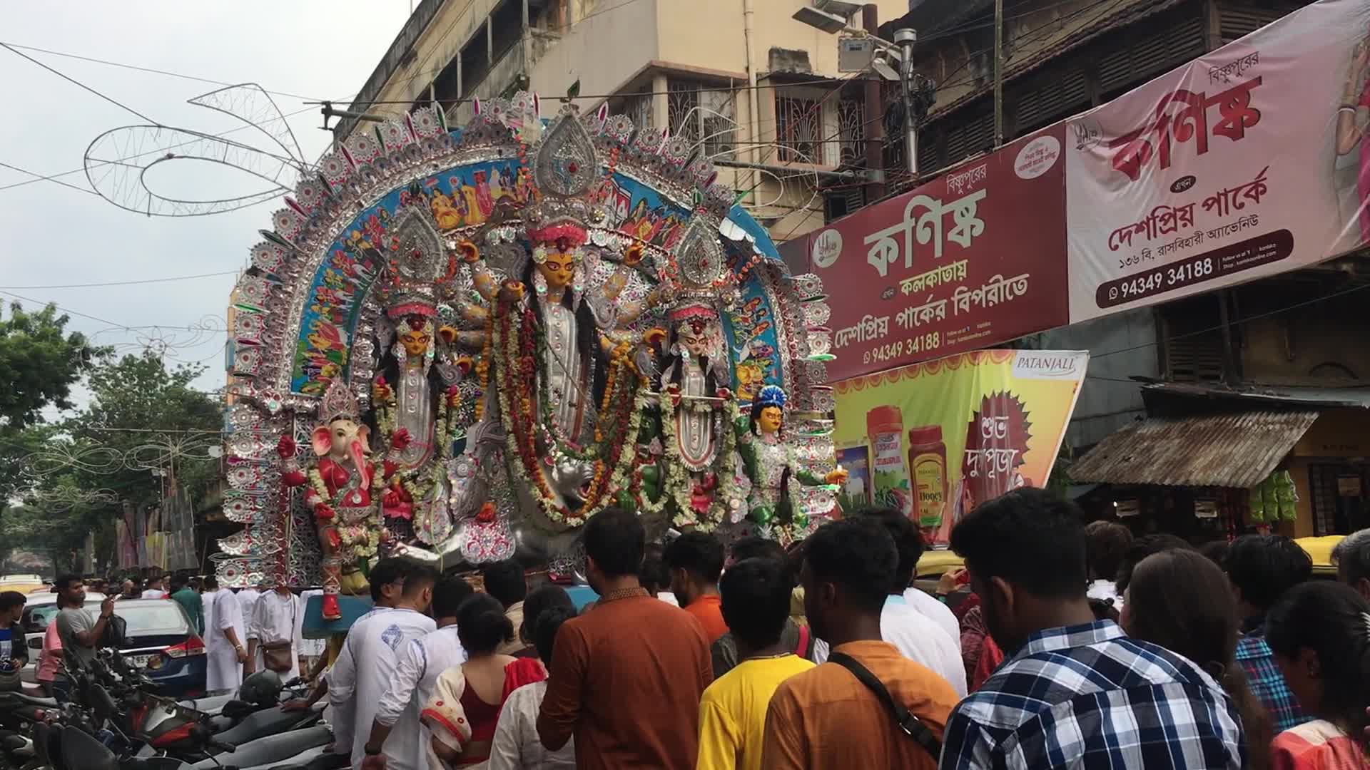 Devotees carry Durga idol through a busy street