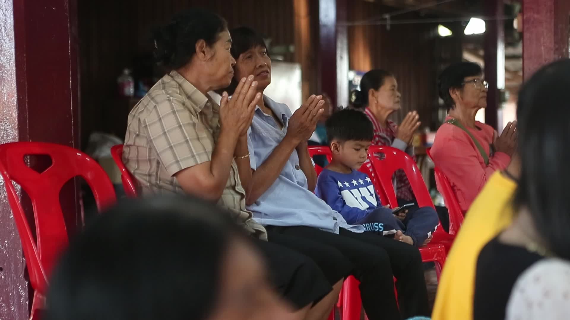 Villagers pray and join in making merit